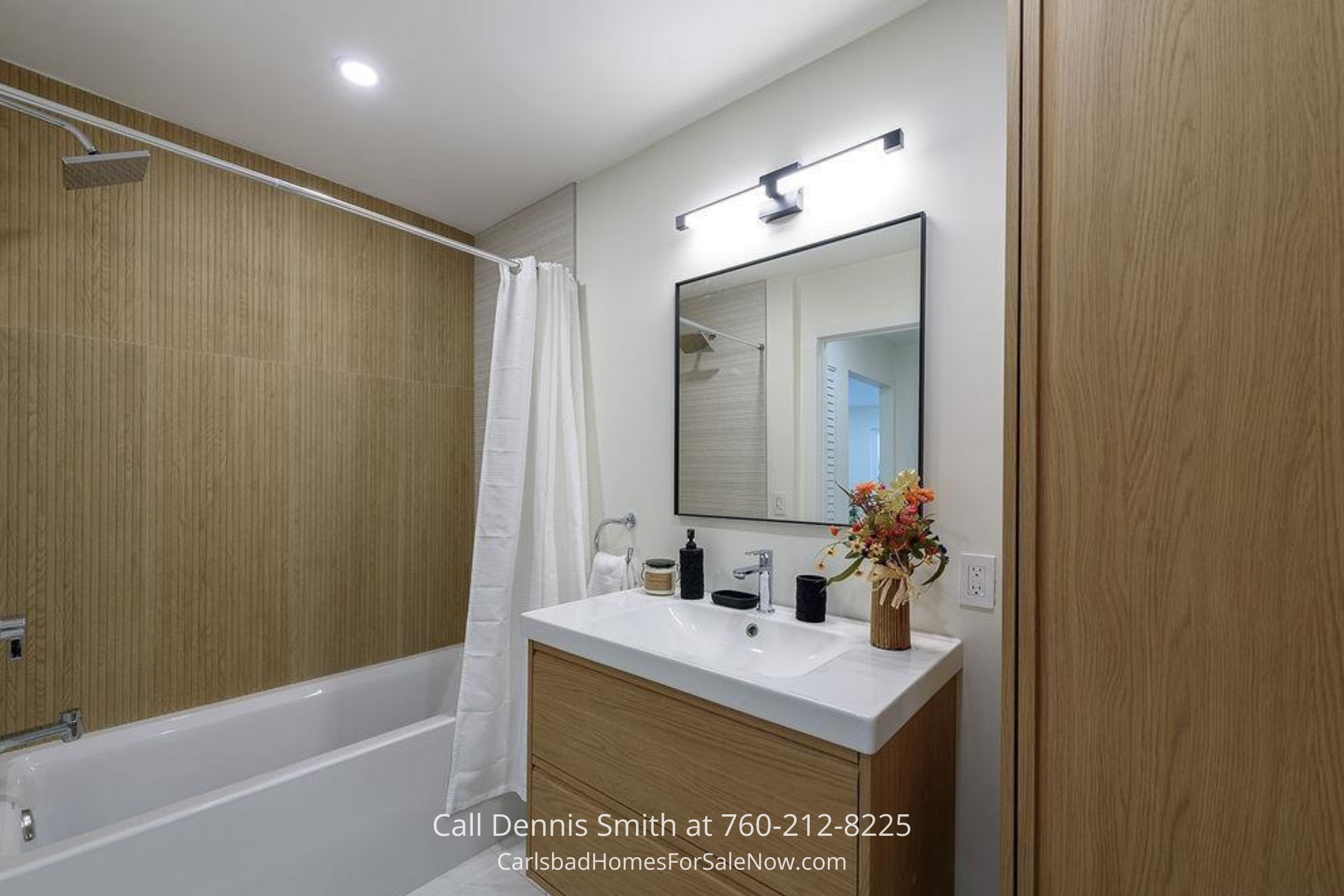 Modern bathroom with wood-accented walls, a full bathtub, sleek vanity, and bright lighting in 930 Via Mil Cumbres Unit 175 Solana Beach condo for sale.